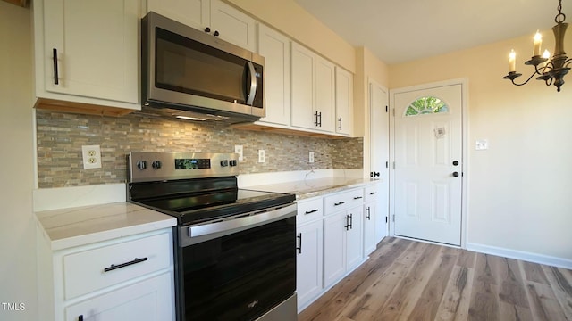 kitchen featuring white cabinetry, light stone countertops, decorative backsplash, and stainless steel appliances