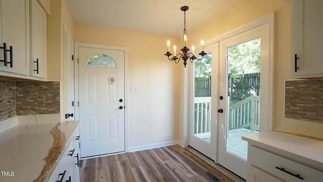 doorway to outside with an inviting chandelier, light hardwood / wood-style floors, and french doors