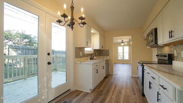 kitchen with sink, appliances with stainless steel finishes, white cabinetry, hardwood / wood-style floors, and decorative backsplash