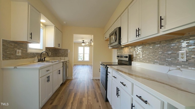 kitchen with tasteful backsplash, appliances with stainless steel finishes, sink, and white cabinets