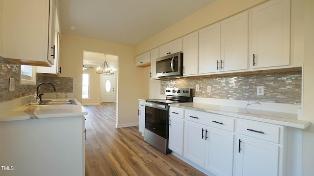 kitchen with white cabinetry, hanging light fixtures, and appliances with stainless steel finishes