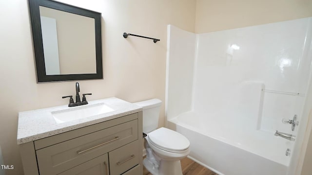 full bathroom featuring hardwood / wood-style flooring, washtub / shower combination, vanity, and toilet