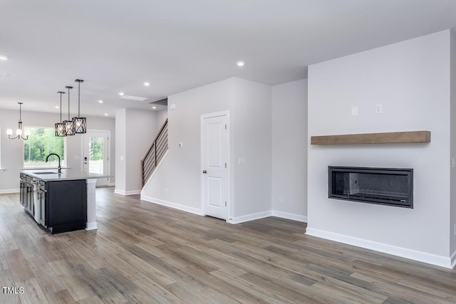 unfurnished living room featuring sink, a notable chandelier, and dark hardwood / wood-style floors