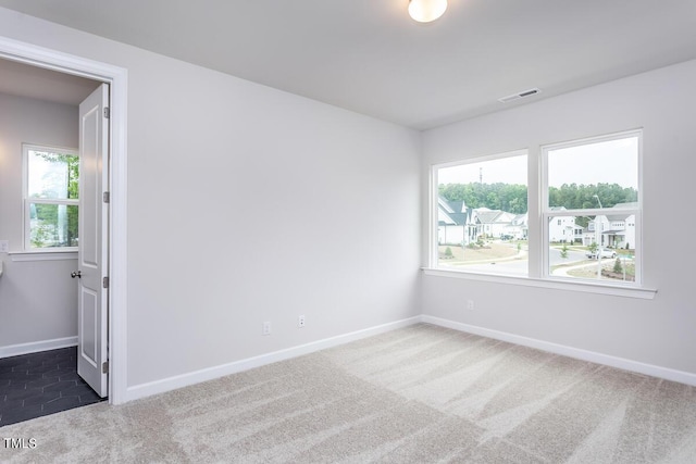 empty room featuring dark carpet and a wealth of natural light