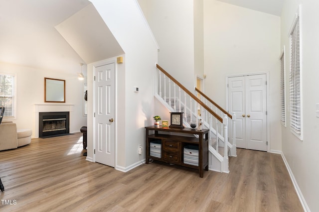 interior space featuring ceiling fan, high vaulted ceiling, and light wood-type flooring