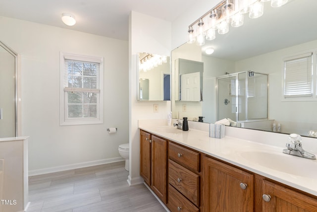 bathroom featuring vanity, a shower with shower door, and toilet