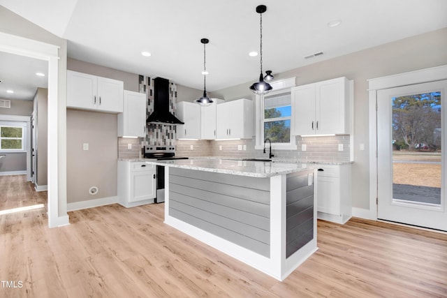 kitchen with white cabinetry, a center island, wall chimney range hood, and stainless steel electric range