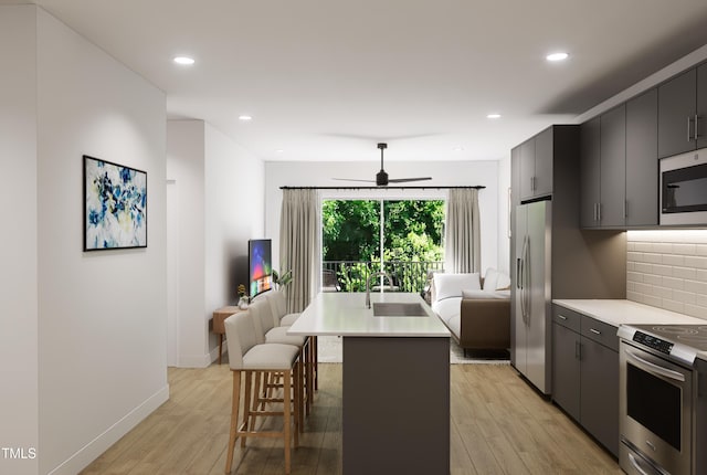 kitchen featuring tasteful backsplash, sink, a kitchen breakfast bar, stainless steel appliances, and a center island with sink