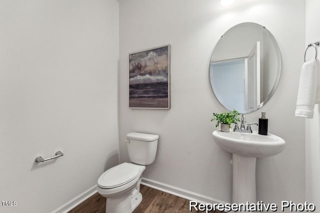 half bath featuring toilet, baseboards, and wood finished floors