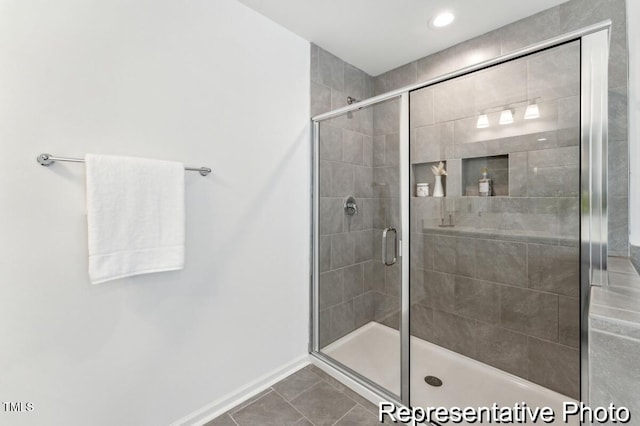 full bathroom with a shower stall, baseboards, and tile patterned flooring