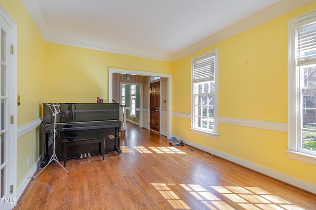 living area featuring visible vents, baseboards, wood finished floors, and crown molding