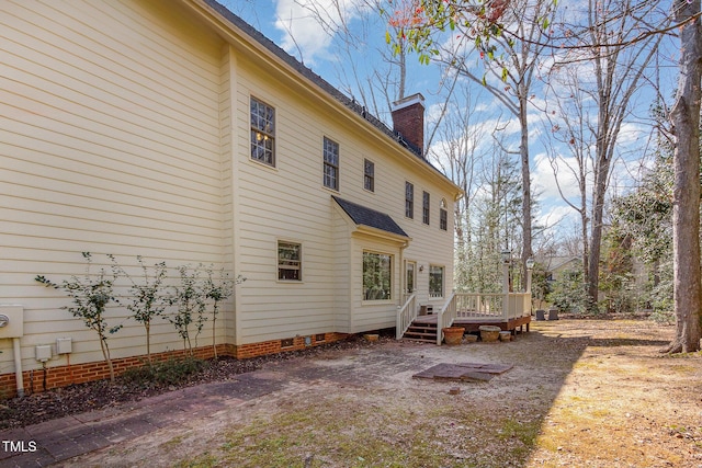 view of side of property featuring a deck, crawl space, and a chimney