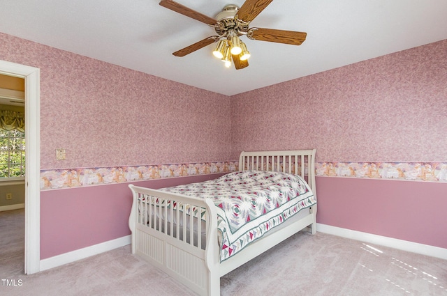 carpeted bedroom with wallpapered walls, a ceiling fan, and baseboards