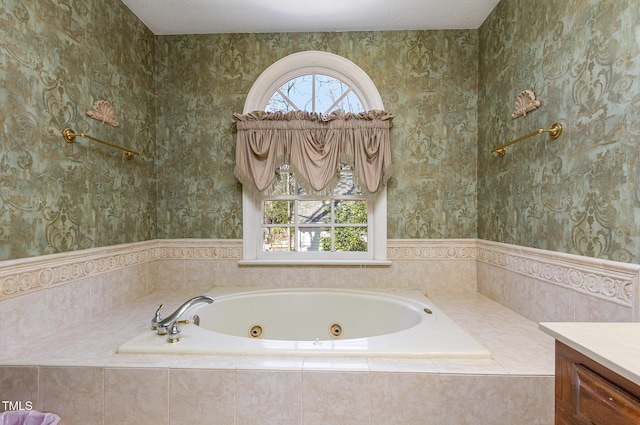 bathroom featuring a tub with jets, vanity, and wallpapered walls