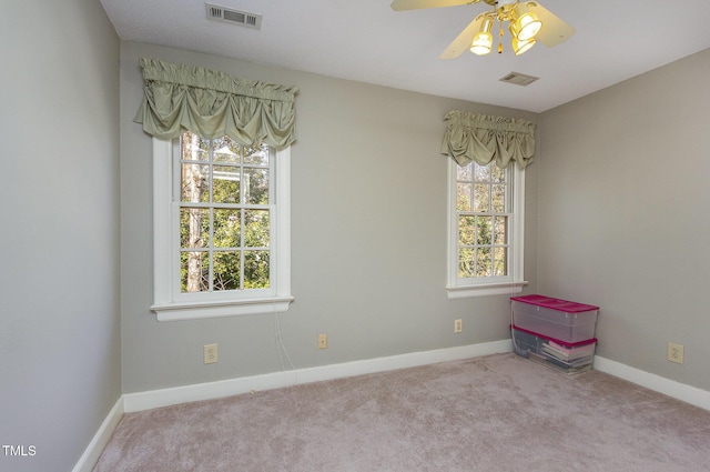 carpeted spare room with visible vents, baseboards, and a ceiling fan