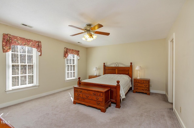 bedroom with visible vents, multiple windows, light colored carpet, and baseboards