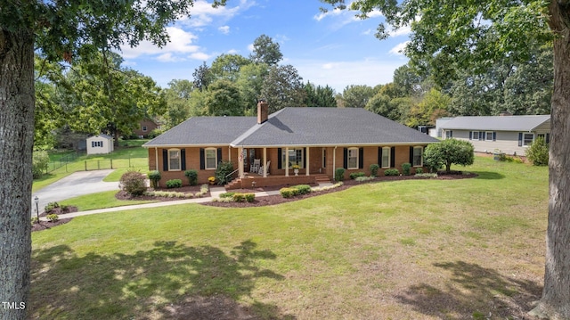 ranch-style home with a front lawn, a storage unit, and covered porch