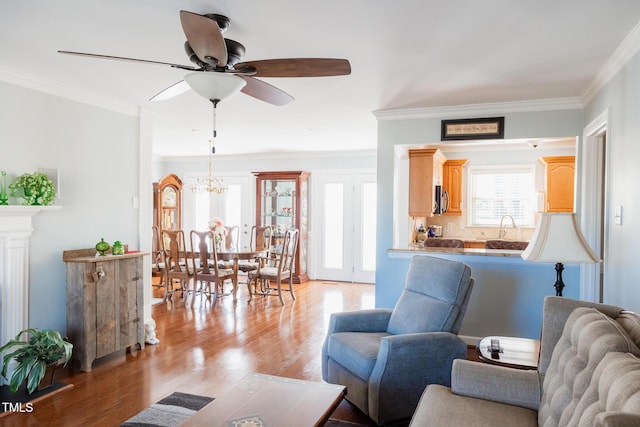 living room with ceiling fan, ornamental molding, sink, and light hardwood / wood-style flooring