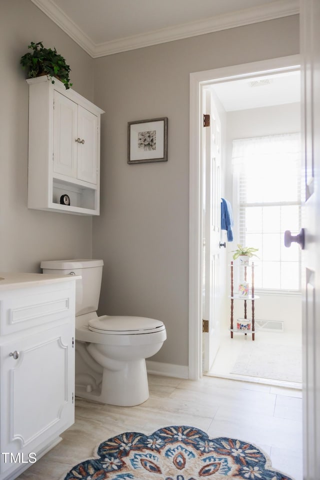 bathroom with crown molding, vanity, and toilet