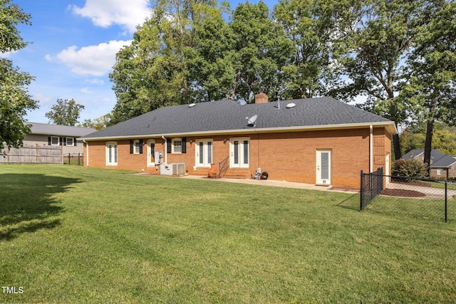 rear view of house featuring cooling unit and a lawn