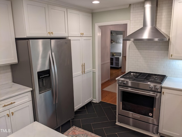 kitchen featuring wall chimney exhaust hood, white cabinetry, ornamental molding, stainless steel appliances, and backsplash