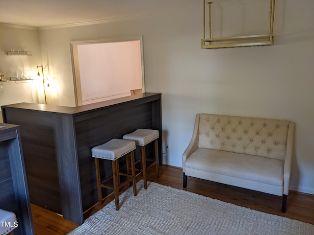 sitting room with dark wood-type flooring, indoor bar, and crown molding