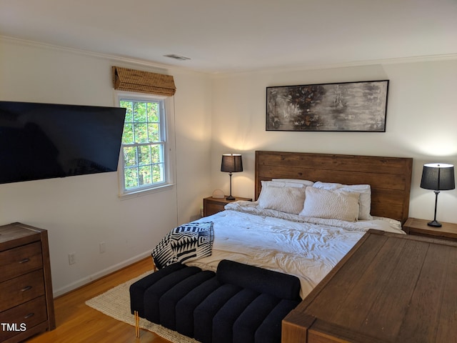 bedroom with ornamental molding and light wood-type flooring