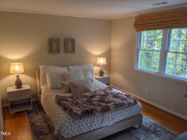 bedroom with multiple windows, crown molding, and wood-type flooring