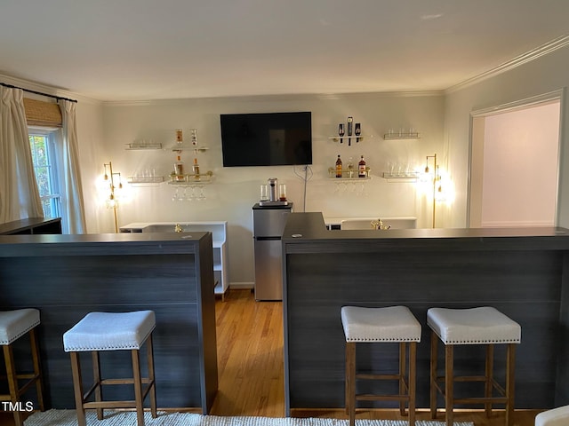 bar with ornamental molding, stainless steel fridge, and light wood-type flooring