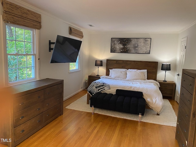 bedroom with multiple windows, ornamental molding, and light hardwood / wood-style flooring