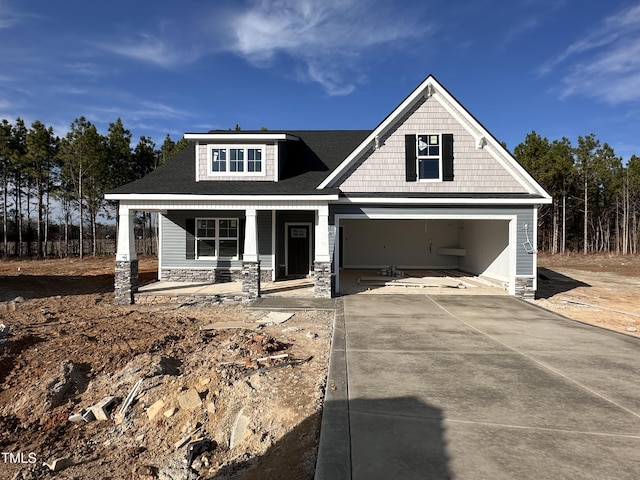 view of front facade with a porch, stone siding, and driveway