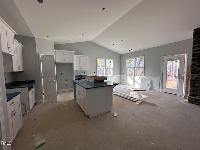 kitchen featuring vaulted ceiling, wainscoting, a kitchen island, and white cabinets