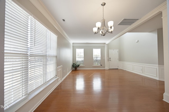 interior space with hardwood / wood-style flooring, ornamental molding, and a notable chandelier