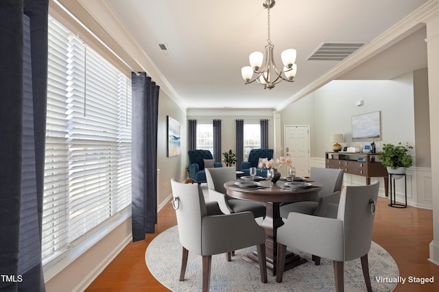 dining space featuring hardwood / wood-style floors, ornamental molding, and a chandelier