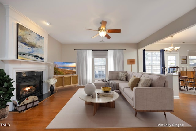 living room featuring hardwood / wood-style floors, ornamental molding, ceiling fan with notable chandelier, and a wealth of natural light