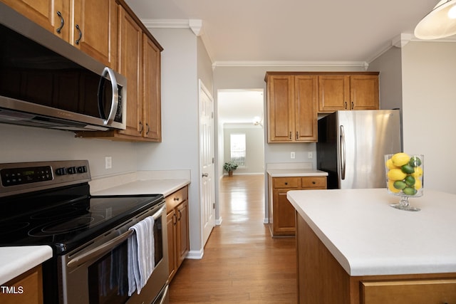 kitchen with stainless steel appliances, ornamental molding, and light hardwood / wood-style floors