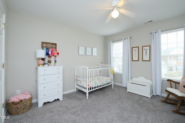 bedroom with ceiling fan, carpet, and a crib