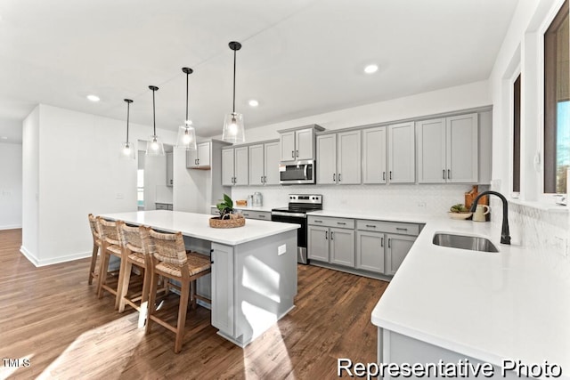 kitchen featuring sink, a breakfast bar area, a center island, hanging light fixtures, and appliances with stainless steel finishes