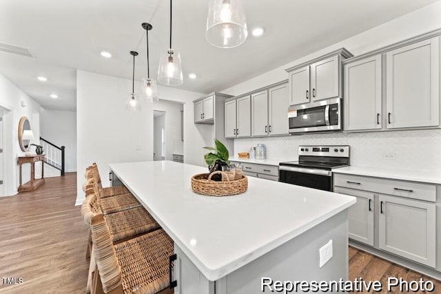 kitchen featuring gray cabinets, appliances with stainless steel finishes, and pendant lighting