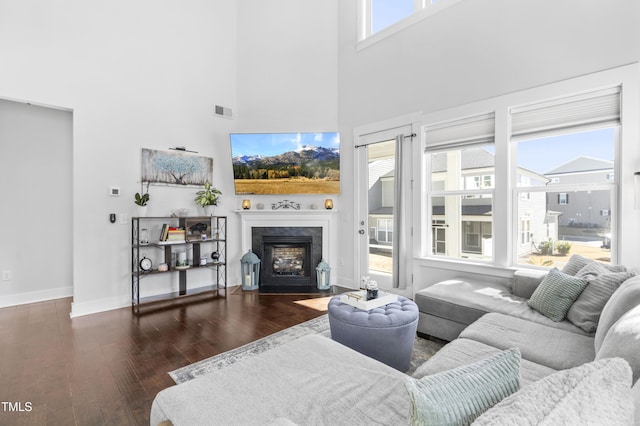 living room featuring a towering ceiling and dark hardwood / wood-style flooring