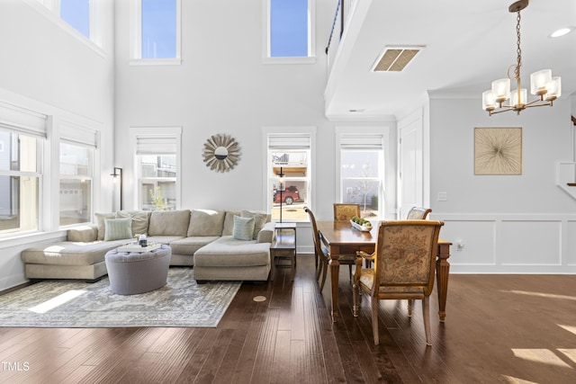 living room with dark hardwood / wood-style floors, a towering ceiling, and an inviting chandelier