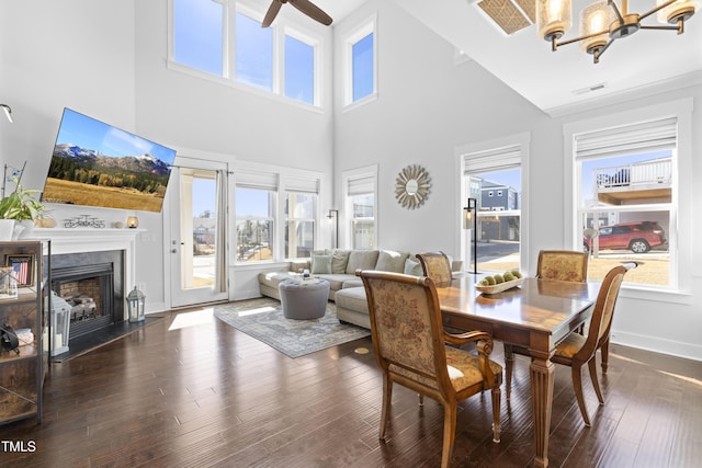 dining room featuring dark hardwood / wood-style floors, ceiling fan with notable chandelier, and a towering ceiling