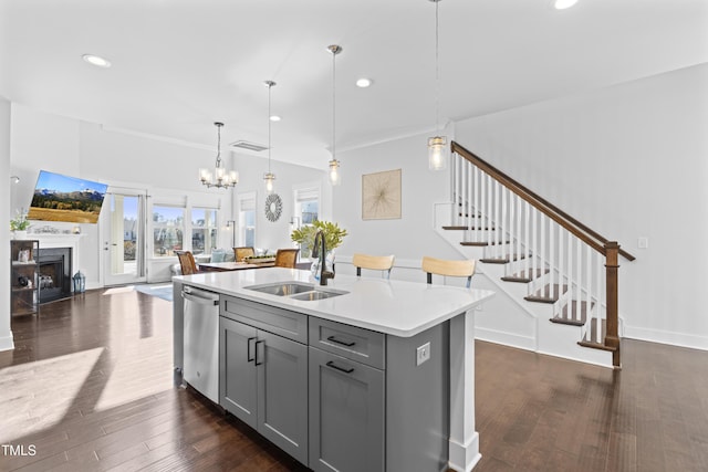 kitchen featuring sink, gray cabinetry, decorative light fixtures, a center island with sink, and dishwasher