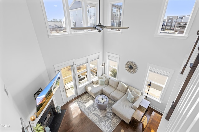 living room featuring dark hardwood / wood-style floors, ceiling fan, and a towering ceiling