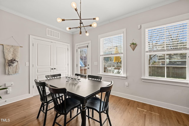 dining area featuring visible vents, baseboards, ornamental molding, wood finished floors, and an inviting chandelier