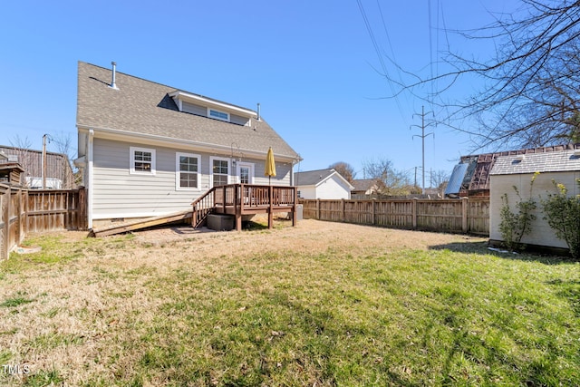 back of house featuring a fenced backyard, a yard, a deck, and roof with shingles