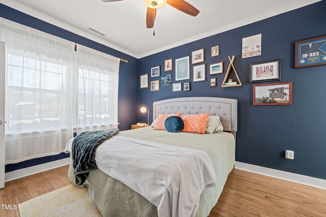 bedroom featuring baseboards, visible vents, ceiling fan, wood finished floors, and crown molding