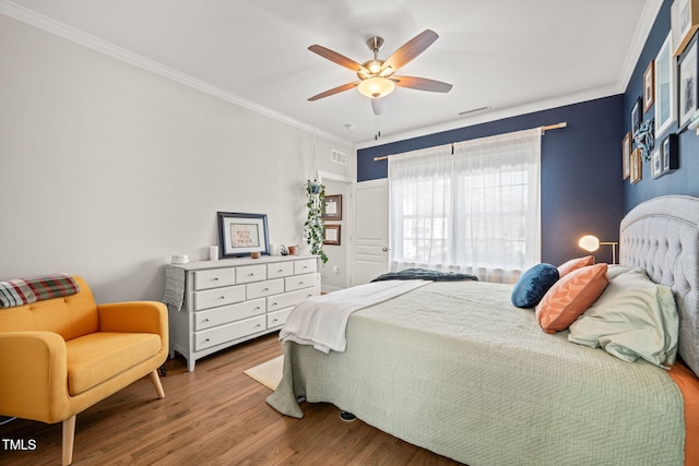 bedroom with ceiling fan, visible vents, crown molding, and wood finished floors