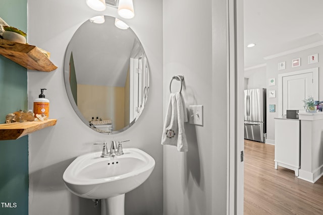 bathroom with baseboards, ornamental molding, wood finished floors, a sink, and recessed lighting