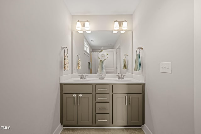 bathroom with double vanity, baseboards, and a sink